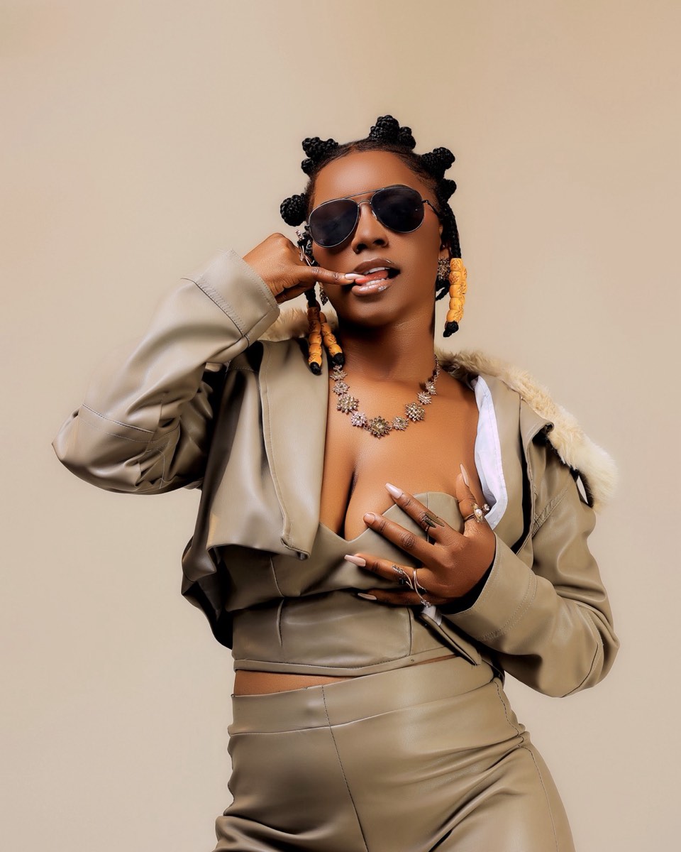 Adea in a taupe leather set and aviators against a warm studio backdrop
